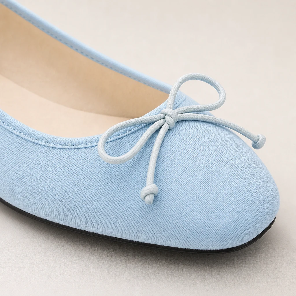 Close-up detail of the flat shoe upper, bow accent, and texture